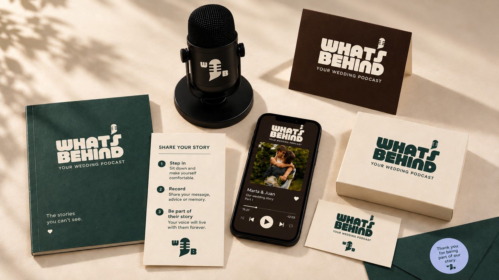 Whats Behind keepsakes on a table: a green book, a cream box, printed cards, a microphone and a phone showing an episode.